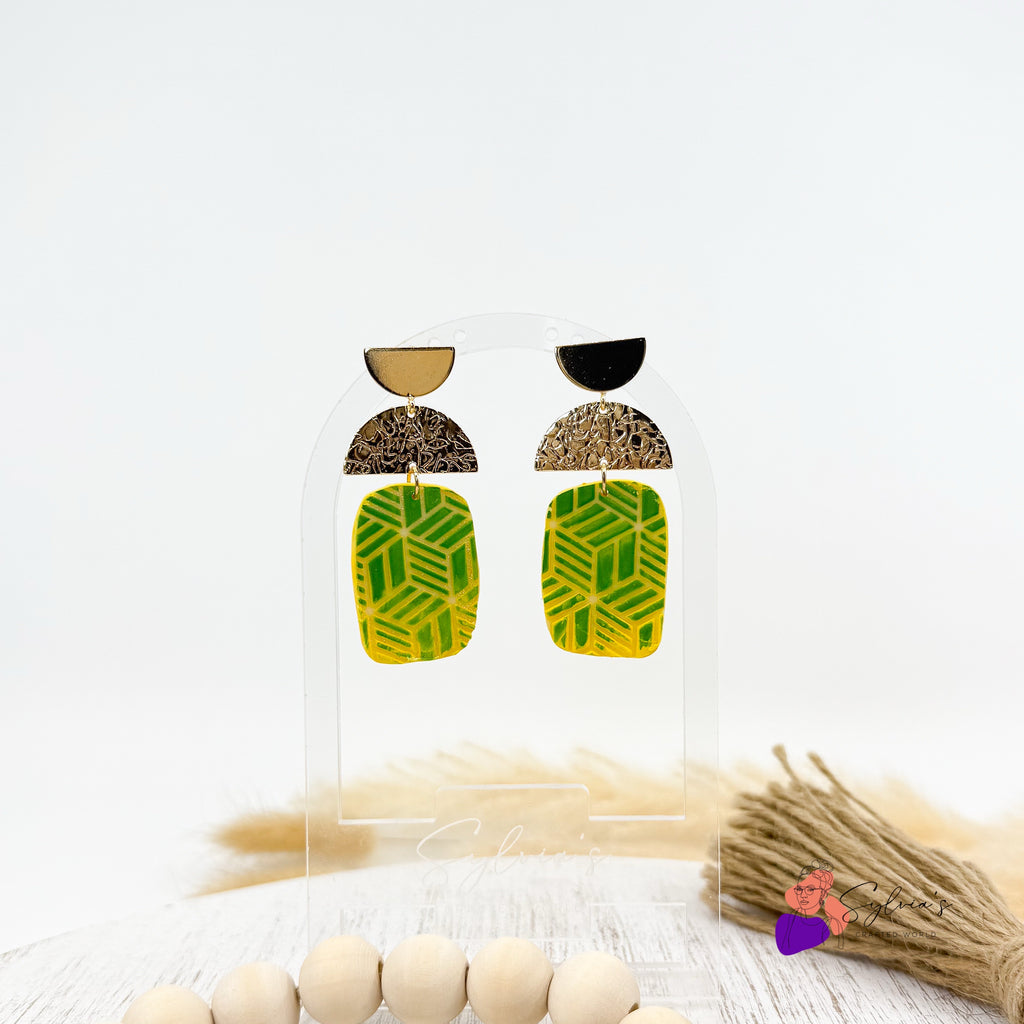 Boucles d’oreilles artisanales en argile polymère vertes et jaunes avec motifs géométriques, demi-lune dorée texturée et support doré – bijoux faits main modernes et légers.