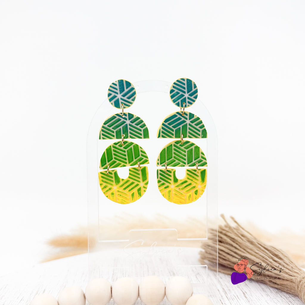 Boucles d’oreilles artisanales en argile polymère vertes et jaunes à motifs géométriques, forme ronde et demi-lune, montées sur support doré – bijoux faits main modernes et légers.