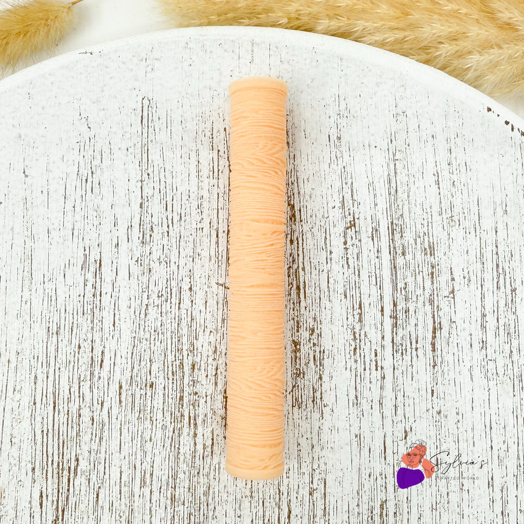 Rouleau texturé effet bois pour créations en argile polymère, vu de dessus sur fond blanc et naturel.