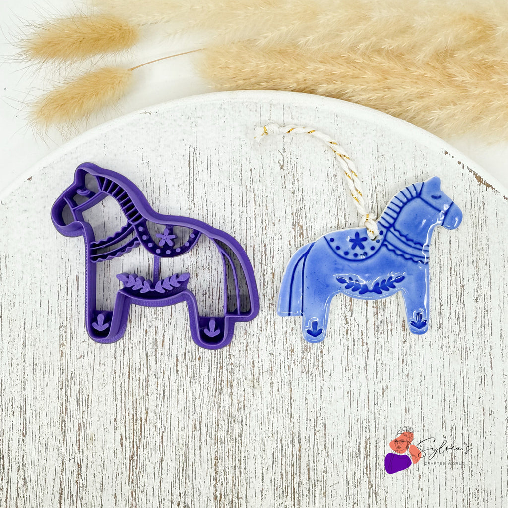 Emporte-pièce cheval scandinave violet pour argile polymère avec exemple de décoration de Noël bleue en forme de cheval.