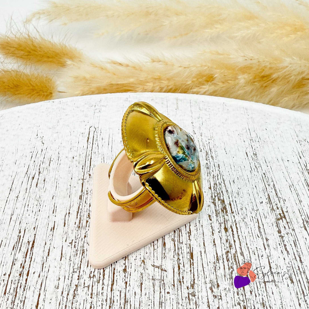 Bague dorée artisanale en argile polymère "Diane" avec motif texturé naturel et monture en acier inoxydable, posée sur support blanc. Bijou unique fait main.