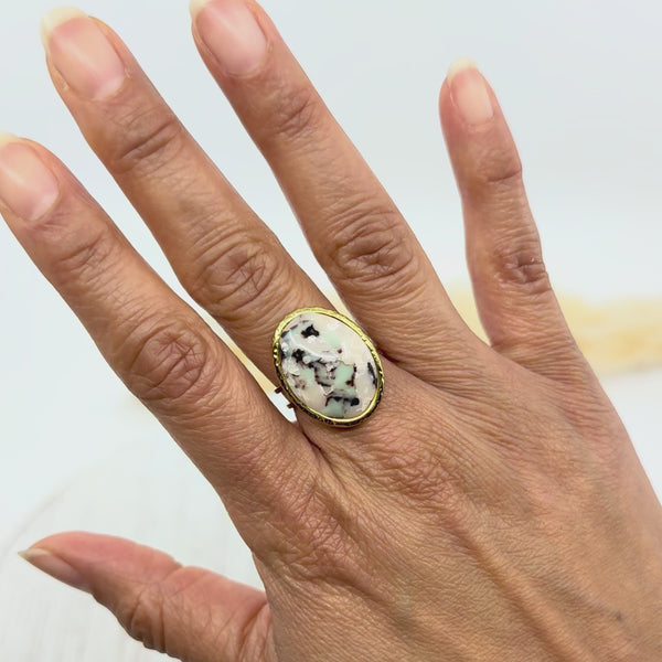 Bague artisanale ovale Clara en argile polymère marbrée, montée sur anneau en acier doré ajustable, portée sur une main féminine. Bijou fait main, léger et hypoallergénique, idéal pour un style unique et élégant.